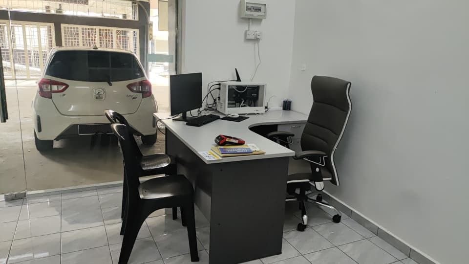 Meja kaunter di dalam pejabat SMA Car Rental, Kuantan, dengan Perodua Myvi putih di luar pintu kaca